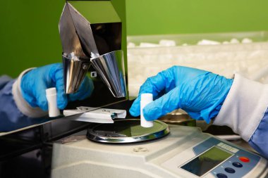 Araştırma asistanı kavanozları ilaçlarla doldurur. Otomatik ilaç teçhizatı üzerine ilaçlar. Tıbbi hazırlıkların üretimi ve üretimi.