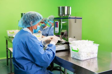 Araştırma asistanı kavanozları ilaçlarla doldurur. Otomatik ilaç teçhizatı üzerine ilaçlar. Tıbbi hazırlıkların üretimi ve üretimi.