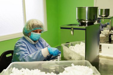 Araştırma asistanı kavanozları ilaçlarla doldurur. Otomatik ilaç teçhizatı üzerine ilaçlar. Tıbbi hazırlıkların üretimi ve üretimi.