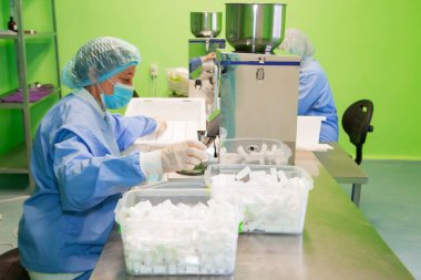 Araştırma asistanı kavanozları ilaçlarla doldurur. Otomatik ilaç teçhizatı üzerine ilaçlar. Tıbbi hazırlıkların üretimi ve üretimi.