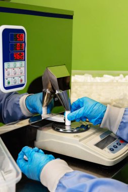 Araştırma asistanı kavanozları ilaçlarla doldurur. Otomatik ilaç teçhizatı üzerine ilaçlar. Tıbbi hazırlıkların üretimi ve üretimi.