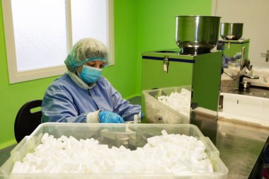 Araştırma asistanı kavanozları ilaçlarla doldurur. Otomatik ilaç teçhizatı üzerine ilaçlar. Tıbbi hazırlıkların üretimi ve üretimi.