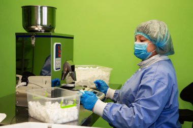 Araştırma asistanı kavanozları ilaçlarla doldurur. Otomatik ilaç teçhizatı üzerine ilaçlar. Tıbbi hazırlıkların üretimi ve üretimi.