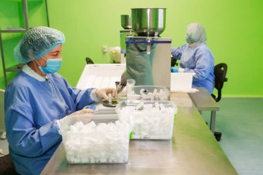 Araştırma asistanı kavanozları ilaçlarla doldurur. Otomatik ilaç teçhizatı üzerine ilaçlar. Tıbbi hazırlıkların üretimi ve üretimi.