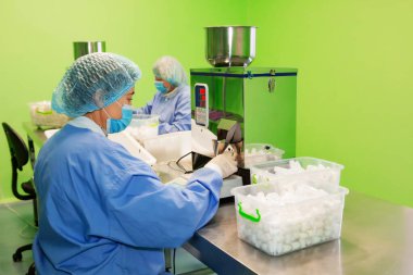 Araştırma asistanı kavanozları ilaçlarla doldurur. Otomatik ilaç teçhizatı üzerine ilaçlar. Tıbbi hazırlıkların üretimi ve üretimi.