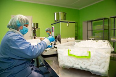 Araştırma asistanı kavanozları ilaçlarla doldurur. Otomatik ilaç teçhizatı üzerine ilaçlar. Tıbbi hazırlıkların üretimi ve üretimi.