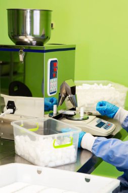 Araştırma asistanı kavanozları ilaçlarla doldurur. Otomatik ilaç teçhizatı üzerine ilaçlar. Tıbbi hazırlıkların üretimi ve üretimi.