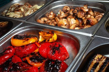 Izgarada pişmiş çeşitli sıcak hazır yemek çeşitleri. Bir sokak fuarında yiyecek satmak. Gidecek sokak yemeği. Fast food. Vejetaryen menüsü.