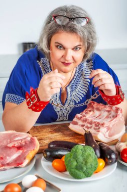 Zincirle kelepçelenmiş, aşırı kilolu, aç, yaşlı bir kadın yiyecek almak istiyor. Kilo verme, diyet yapma, sağlıklı beslenme.