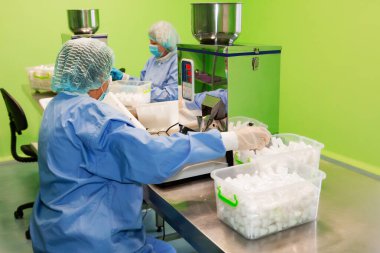 Araştırma asistanı kavanozları ilaçlarla doldurur. Otomatik ilaç teçhizatı üzerine ilaçlar. Tıbbi hazırlıkların üretimi ve üretimi.