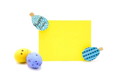 Beyaz arka planda saçılmış renkli yumurtaları olan çamaşır mandallarıyla dolu boş bir kart. Uzayı kopyala Metin için boş alan. Mutlu Paskalyalar! Paskalya geleneksel el yapımı boyanmış yumurtalar.