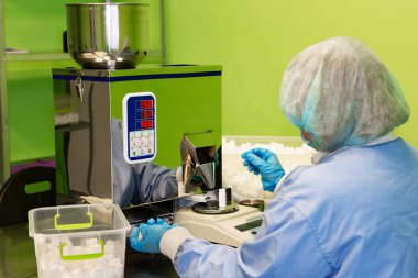 Araştırma asistanı kavanozları ilaçlarla doldurur. Otomatik ilaç teçhizatı üzerine ilaçlar. Tıbbi hazırlıkların üretimi ve üretimi.