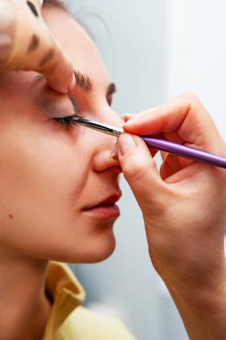 Makyaj sanatçısı, profesyonel bir kuaförde genç ve güzel bir kıza makyaj yapıyor. Güzellik, moda ve cilt bakımı endüstrisi. Makyaj sanatçısının işi..