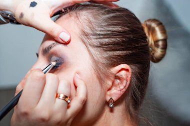 Makyaj sanatçısı, profesyonel bir kuaförde genç ve güzel bir kıza makyaj yapıyor. Güzellik, moda ve cilt bakımı endüstrisi. Makyaj sanatçısının işi..