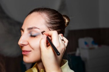 Makyaj sanatçısı, profesyonel bir kuaförde genç ve güzel bir kıza makyaj yapıyor. Güzellik, moda ve cilt bakımı endüstrisi. Makyaj sanatçısının işi..