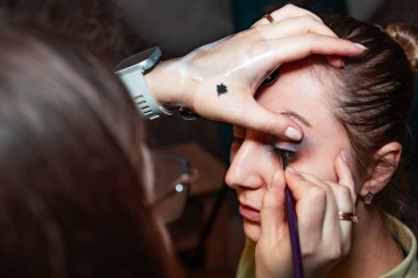 Makyaj sanatçısı, profesyonel bir kuaförde genç ve güzel bir kıza makyaj yapıyor. Güzellik, moda ve cilt bakımı endüstrisi. Makyaj sanatçısının işi..