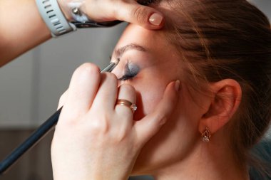 Makyaj sanatçısı, profesyonel bir kuaförde genç ve güzel bir kıza makyaj yapıyor. Güzellik, moda ve cilt bakımı endüstrisi. Makyaj sanatçısının işi..