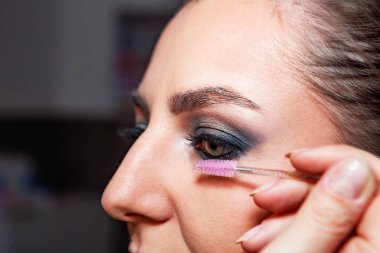 Makyaj sanatçısı, profesyonel bir kuaförde genç ve güzel bir kıza makyaj yapıyor. Güzellik, moda ve cilt bakımı endüstrisi. Makyaj sanatçısının işi. Kirpiklere rimel sürüyorum..