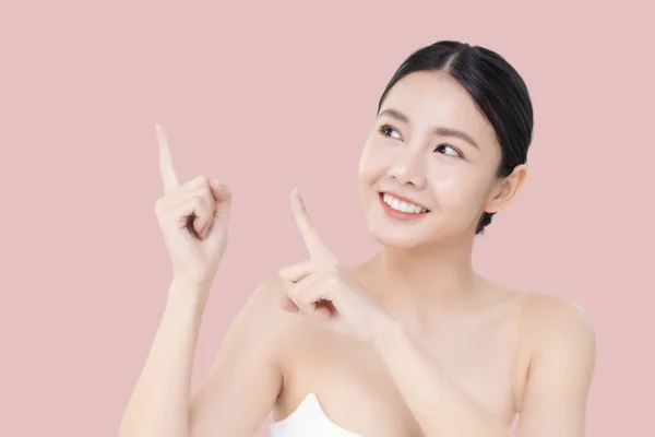 스튜디오는 배경에 깨끗하고 피부를 가리키는 손가락을 아름다운 아시아 여성을 관리의아름다움 — 스톡 사진