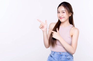 Asyalı gülümseyen kadın parmak göstererek kenarı işaret ediyor. Beyaz arkaplanda kopya alanı ile izole edilmiş..