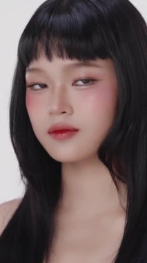 Dikey güzel Asyalı kız makyajlı ve sağlıklı tenli soyutlanmış beyaz arka planda. Ticari reklamlar için ergen yüz ve cilt bakımı kavramı.