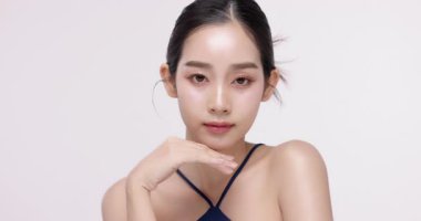 Işıl ışıl cildi ve K-Güzeli olan güzel Asyalı kızın yavaş çekimleri. Ticari güzellik reklamları için izole edilmiş beyaz arka planda makyaj stili..