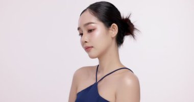 Işıl ışıl cildi ve K-Güzeli olan güzel Asyalı kızın yavaş çekimleri. Ticari güzellik reklamları için izole edilmiş beyaz arka planda makyaj stili..