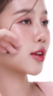 Dikey görüntüler, sağlıklı ciltli güzel Asyalı kadın beyaz arka planda ticari ürün reklamcılığı için izole edilmiş. Yavaş çekim..