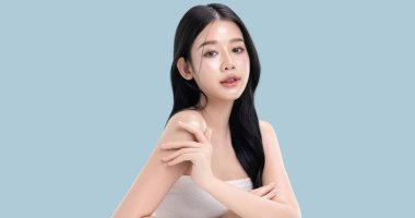 Parlayan ten, mavi arka planda izole edilmiş güzel, genç Asya modelinin makyaj stili..