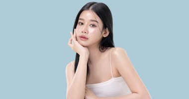 Parlayan ten, mavi arka planda izole edilmiş güzel, genç Asya modelinin makyaj stili..