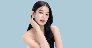 Parlayan ten, mavi arka planda izole edilmiş güzel, genç Asya modelinin makyaj stili..