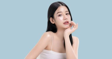 Parlayan ten, mavi arka planda izole edilmiş güzel, genç Asya modelinin makyaj stili..