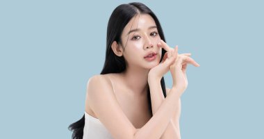 Parlayan ten, mavi arka planda izole edilmiş güzel, genç Asya modelinin makyaj stili..