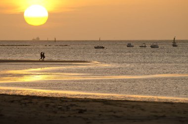 Gün batımında sahilde gezinen bir çift. Bonanza Plajı. Sanlucar de Barrameda. Cadiz. Endülüs. İspanya.