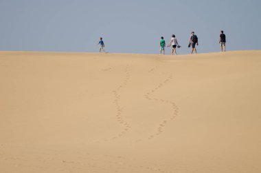 Kum tepesinde yürüyen bir aile. Maspalom Kumulları 'nın Özel Doğal Rezervi. Maspalomalar. Büyük Kanarya. Kanarya Adaları. İspanya.