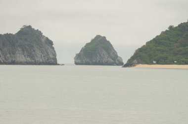 Kireçtaşı kayalıkları ve kumlu plaj. Ian Ha Bay. Kedi Ba Takımadası. Vietnam.