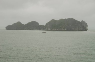 Kireçtaşı kayalığı ve balıkçı teknesi. Ian Ha Bay. Kedi Ba Takımadası. Vietnam.