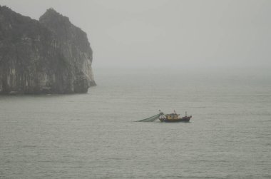 Balıkçı teknesi ve kireçtaşı kayalığı. Ian Ha Bay. Kedi Ba Takımadası. Vietnam.