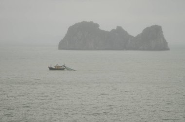 Balıkçı teknesi ve kireçtaşı kayalığı. Ian Ha Bay. Kedi Ba Takımadası. Vietnam.