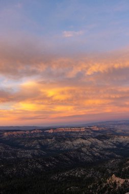 Bryce Canyon Ulusal Parkı 'nın üzerindeki renkli günbatımı gökyüzü engebeli arazisi ve kaya oluşumlarıyla güzelce harmanlanarak bu çarpıcı yerin görkemli manzarasını güzelleştiriyor.