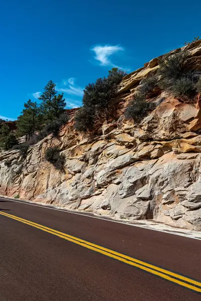 Açık mavi gökyüzünün altında, Utahs Bryce Canyon Ulusal Parkı 'nın kaya oluşumlarının arasından geçen manzaralı bir yol doğanın güzelliğini gözler önüne seriyor ve keşif için huzurlu bir ortam sunuyor.