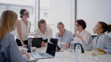 Bir grup genç iş adamı modern bir ofiste iş birliği yapıp, başarı planları yapıyorlar. Çeşitli çalışanlar, takım çalışması ve iletişim üzerine yoğunlaşarak verimli bir oturum gerçekleştiriyorlar.