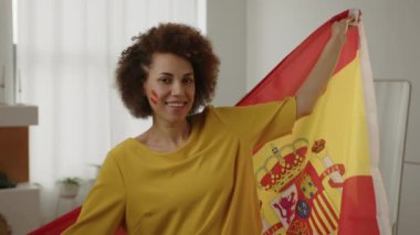 Mutlu İspanyol futbol fanatiği, yanaklarında boyalı bayraklarla favori İspanya takımı için tezahürat yapıyor. Avrupa spor futbolu. Futbol kupası 2026 ABD, Kanada, Meksika. Spor ve futbol hayranları. Yavaş Hareket