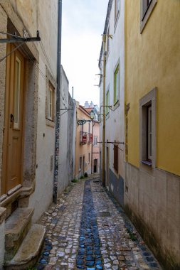 Lisbons 'un tarihi kasabasında sembolik mimarisi ve renkli cepheleriyle bilinen kaldırım taşlı bir ara sokağın cazibesini keşfedin. Manzara ve açık hava aktiviteleri için popüler bir hedef.