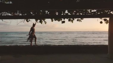 Zarif bir kadın gün batımında okyanusun kenarında bir pergola altında dans eder. Güzel deniz manzarasına karşı çarpıcı bir siluet oluşturur. Hareketleri sayesinde zarafet ve özgürlük yayar.