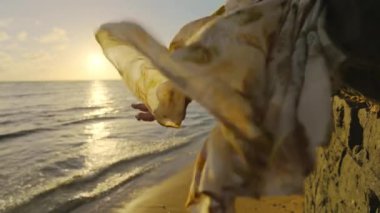 Gün batımında rüzgarda dalgalanan bir elbiseyle okyanusta sakin bir an. Rahatlamayı, doğal güzelliği ve huzuru simgeliyor. Bohem bir ortamda barış ve uyumu çağrıştırıyor.