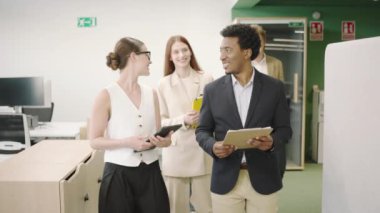 Modern bir ofiste işbirliği yapan ve bir iş toplantısına katılan bir grup profesyonel. Başarılı genç çalışanlar tablet ve belgelerle şirket stratejilerini tartışıyor ve yürüyor..