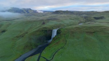 Yeşilliklerle çevrili İzlanda 'daki görkemli şelale, yüksek bir perspektiften doğanın dingin cazibesini gösteren, sinematik bir dron çekimine güzelce yakalandı.