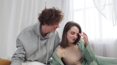 Genç bir çift evlerinde rahat ve aydınlık bir odada kaynaşıyor ve huzurlu bir sabahın tadını çıkarıyor.