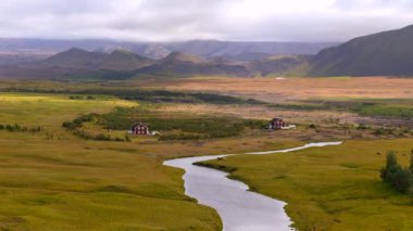 İzlanda 'nın engin platolarında nefes kesici hava manzarası yayılıyor. Uzak karlı dağlara uzanan çorak arazilerin geniş manzarası. Nehir İzlanda' nın katıksız güzelliğini simgeliyor.. 